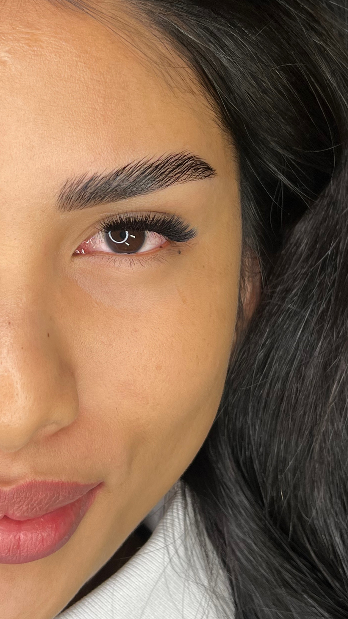 Close-up of a person's brown eye with long eyelashes, showcasing detailed texture and natural eye color.