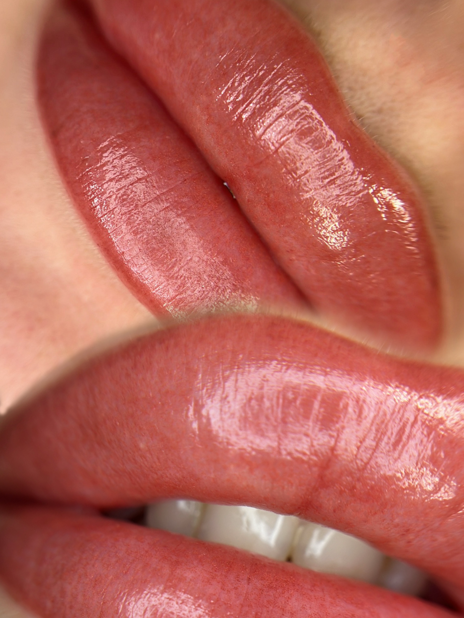 Close-up of two glossy, pink, plump lips.