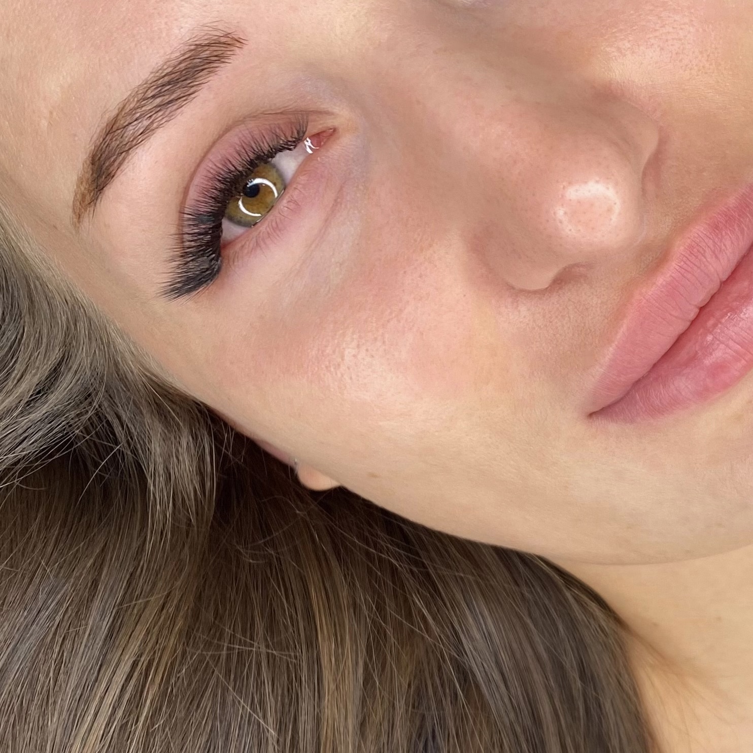 Close-up of a person's brown eye with long eyelashes, showcasing detailed texture and natural eye color.